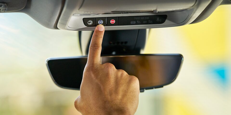 A Person Reaching For the OnStar Button on the Rearview Mirror in Their Vehicle