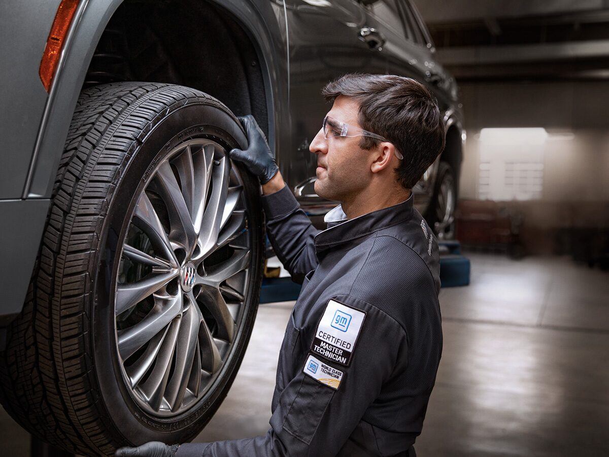 A Male Service Tech Installing a Tire on a Raised Vehicle