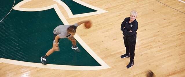 MSU Basketball Coach Suzy Merchant Stands on Court with Player