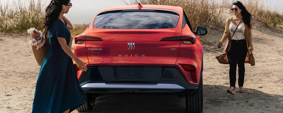 A Couple Sits on the Trunk of Their Buick Enclave While Enjoying the Breathtaking Views of the Mountains