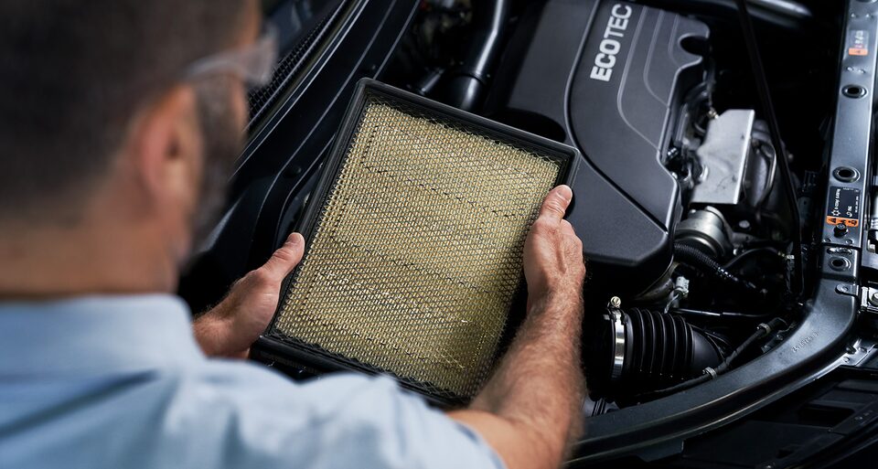 Certified Service Technician inspecting dirty engine air filter