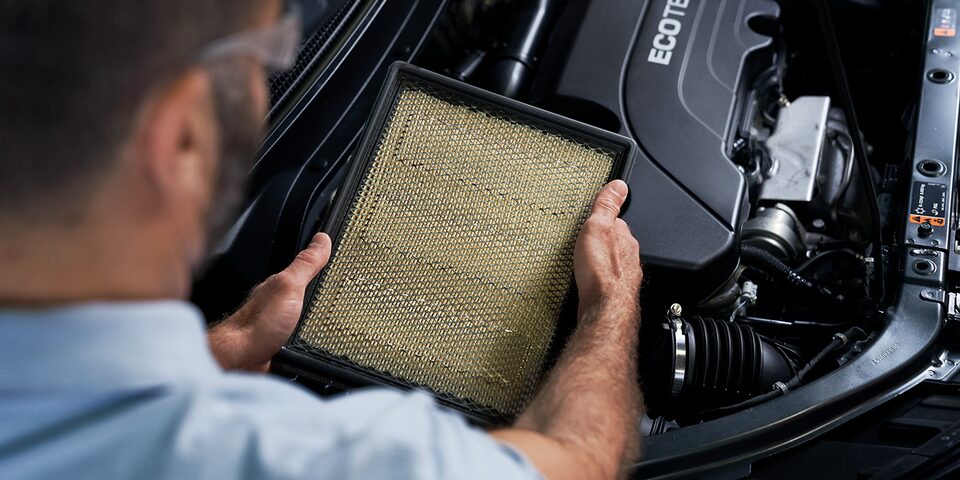 Certified Service Technician inspecting dirty engine air filter