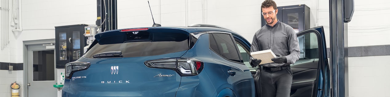 Mechanic Standing Next to a Blue Chevrolet Vehicle with It’s Front Passenger Door Open