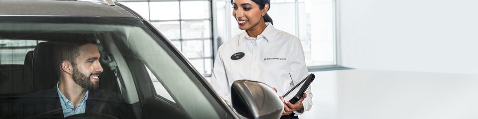 Buick Certified Service Representative Speaking with a Buick Customer Sitting in Their Car