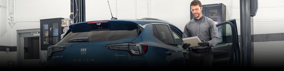 A Male Technician Inspecting a White Vehicle’s Tire While It’s Suspended in the  Air