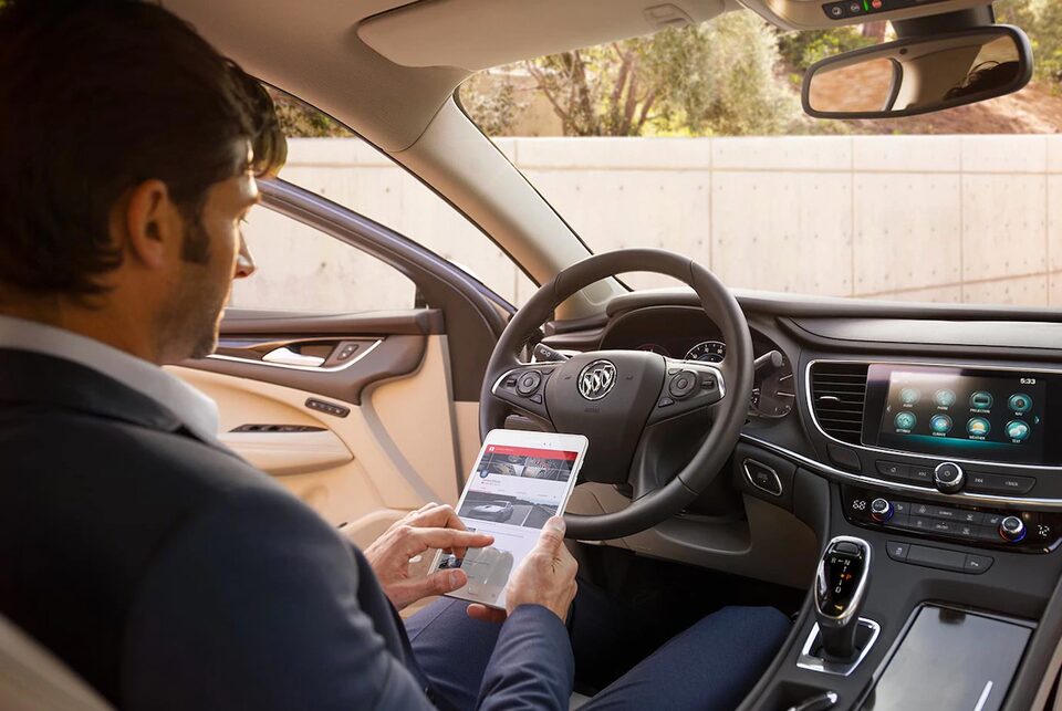 Image of a man using a tablet to access the convenient in-car Wi-Fi hotspot in his Buick vehicle.