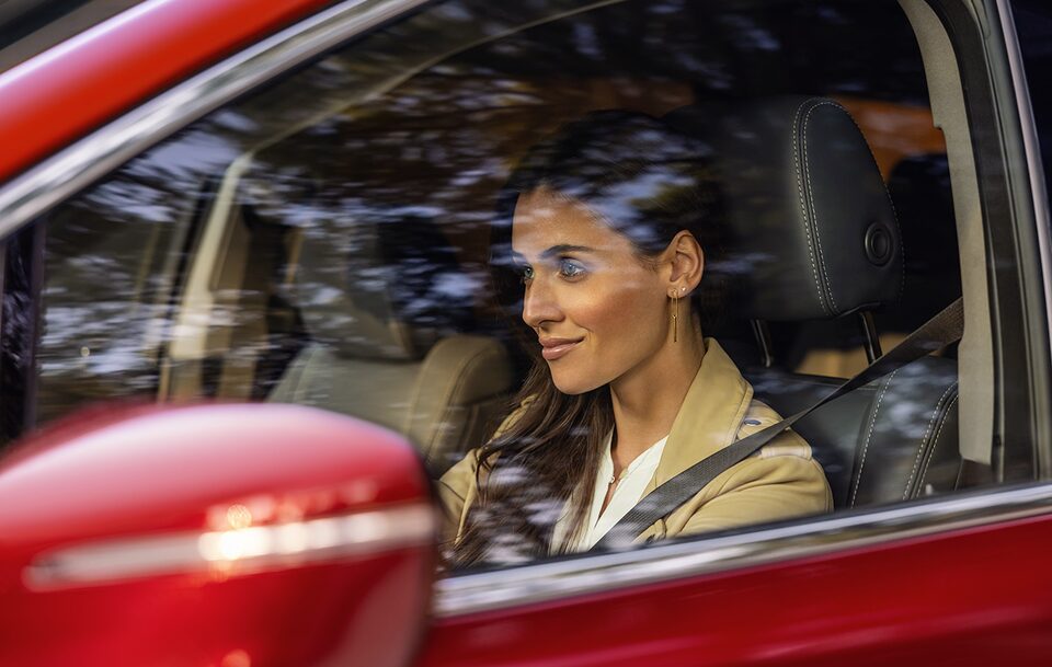 A Women Driving a Stunning Red Buick With Trees Reflecting in the Mirror