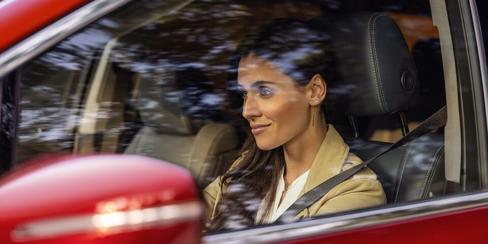A Women Driving a Stunning Red Buick With Trees Reflecting in the Mirror