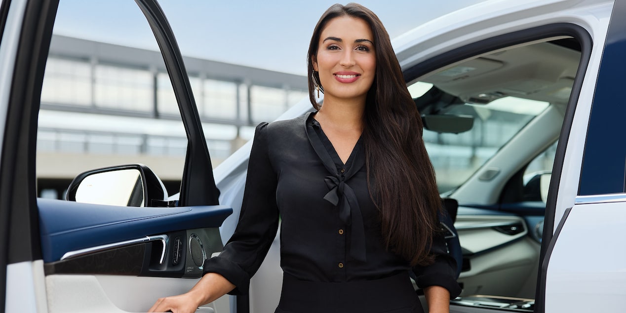 Dalia Elmokadem Stands Smiling by the Open Driver's Side Door of a White Buick Vehicle with Blue and White Interior Accents