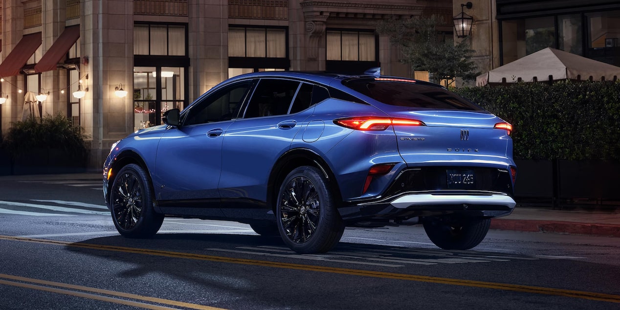 A Blue Buick SUV Parked on a City Street at Night with Taillights Illuminated and the Buick Logo Visible