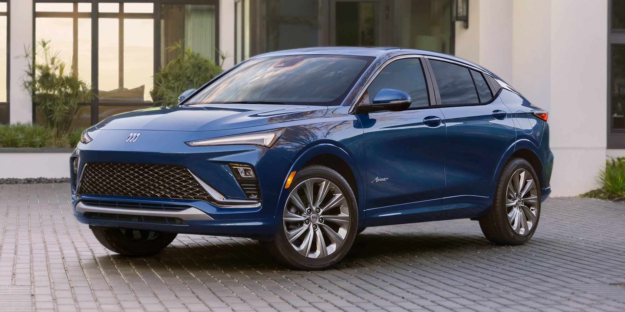 A Dark Blue Buick Envista Parked on a Gray Paved Driveway in Front of a Modern Building