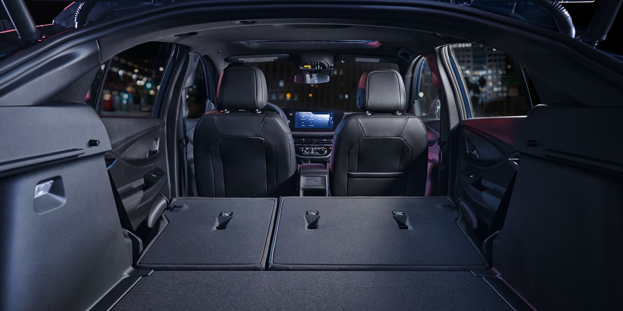 The Open Trunk of a Buick Vehicle with Rear Seats Folded Down Revealing Spacious Cargo Area at Night