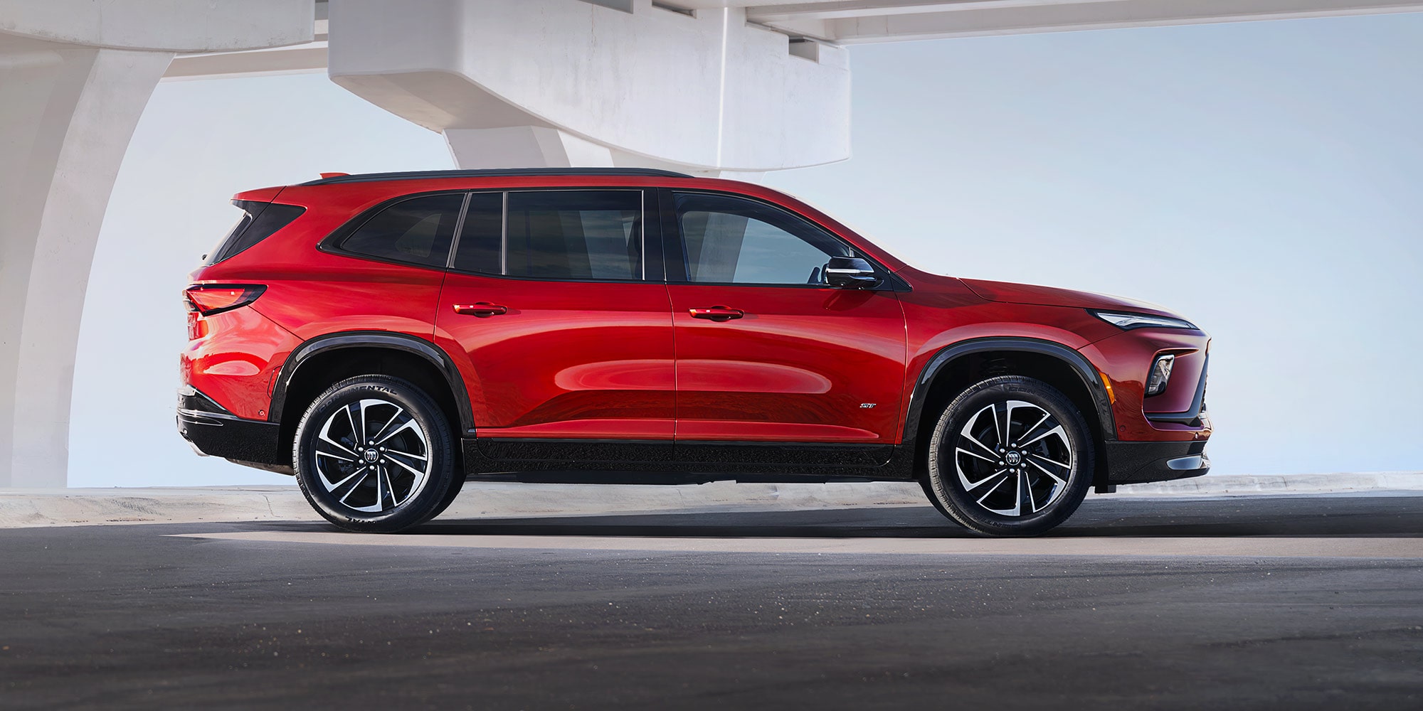 Red Buick Encore GX SUV Parked Under a Concrete Elevated Structure in a Minimalist Setting