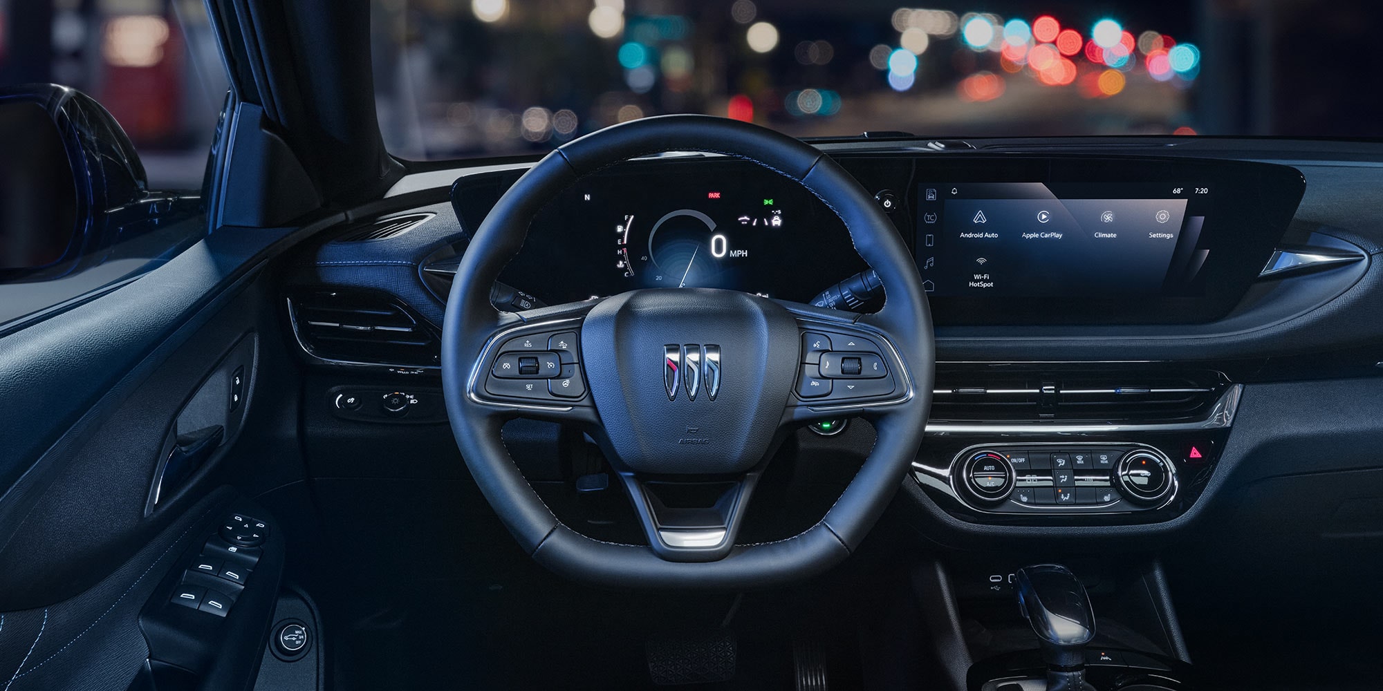 Driver's View of a Buick Interior at Night with Illuminated Digital Displays and City Lights