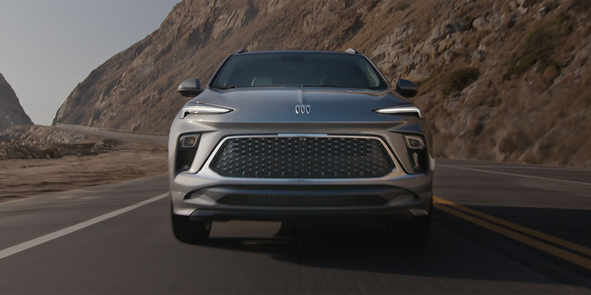 A Gray Buick Encore GX Driving on a Winding Road Along a Rocky Coastline