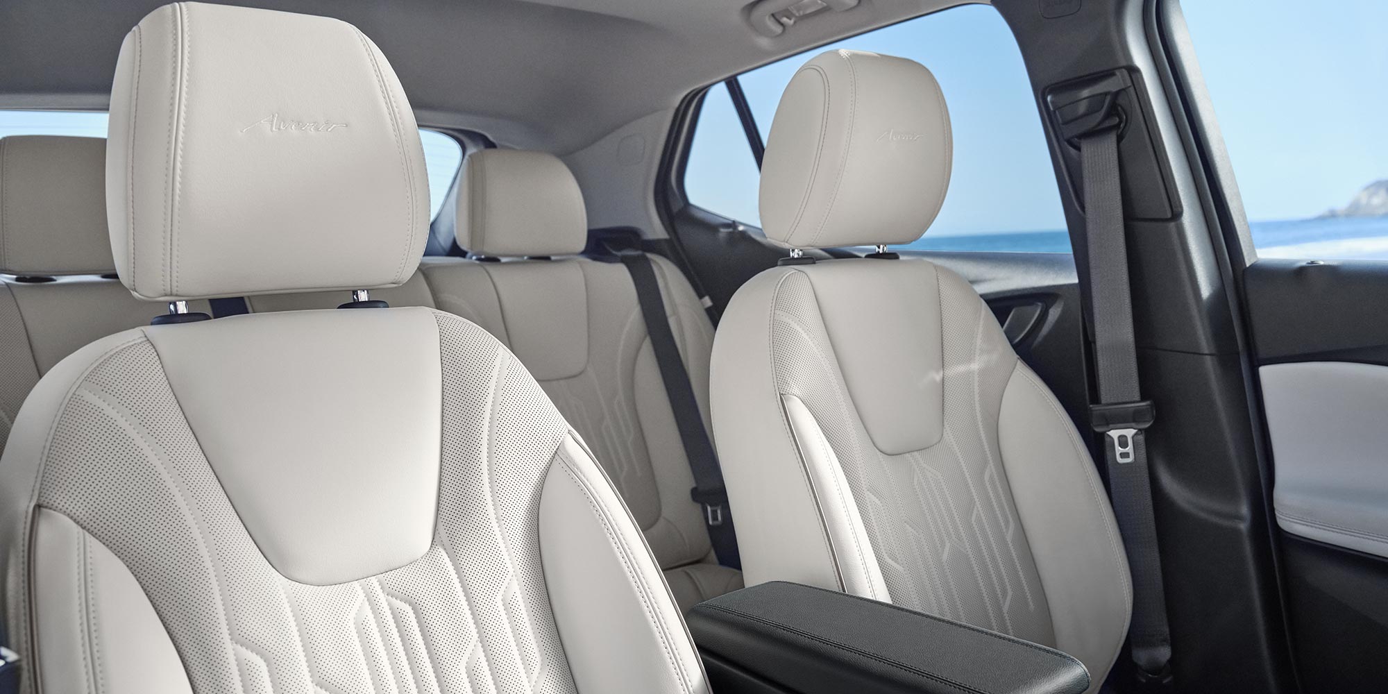 An Interior View of a Buick Avenir with White Leather Front and Rear Seats and an Armrest with the Ocean Visible Outside