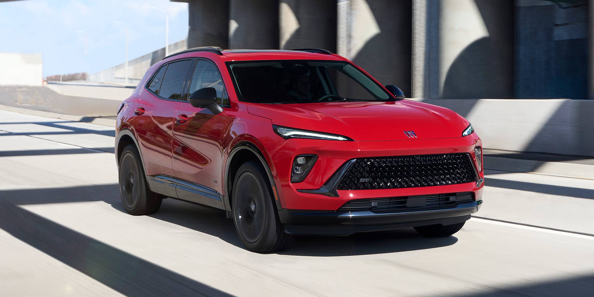 A Red Buick SUV Driving on a Multi-Lane Highway Under an Overpass Structure During the Daytime