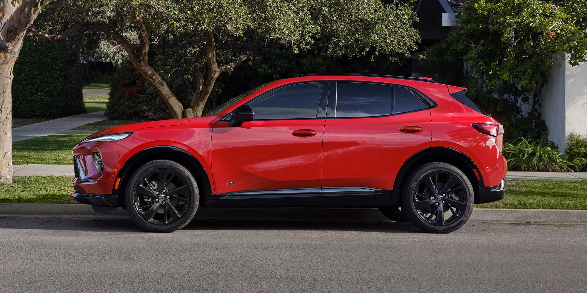 A Red Buick Envision Parked on a Street with Trees in the Background