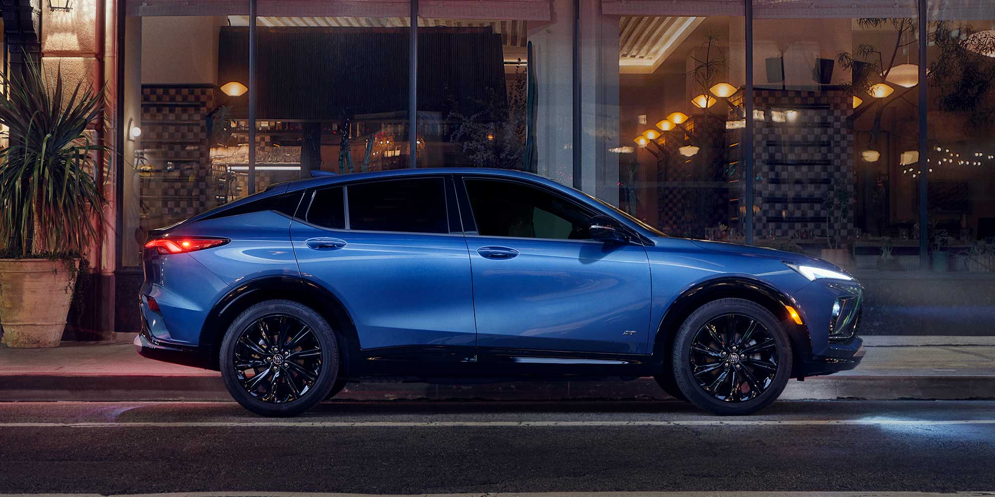 A Blue Buick Envista Parked at Night in Front of a Building with Lit Windows