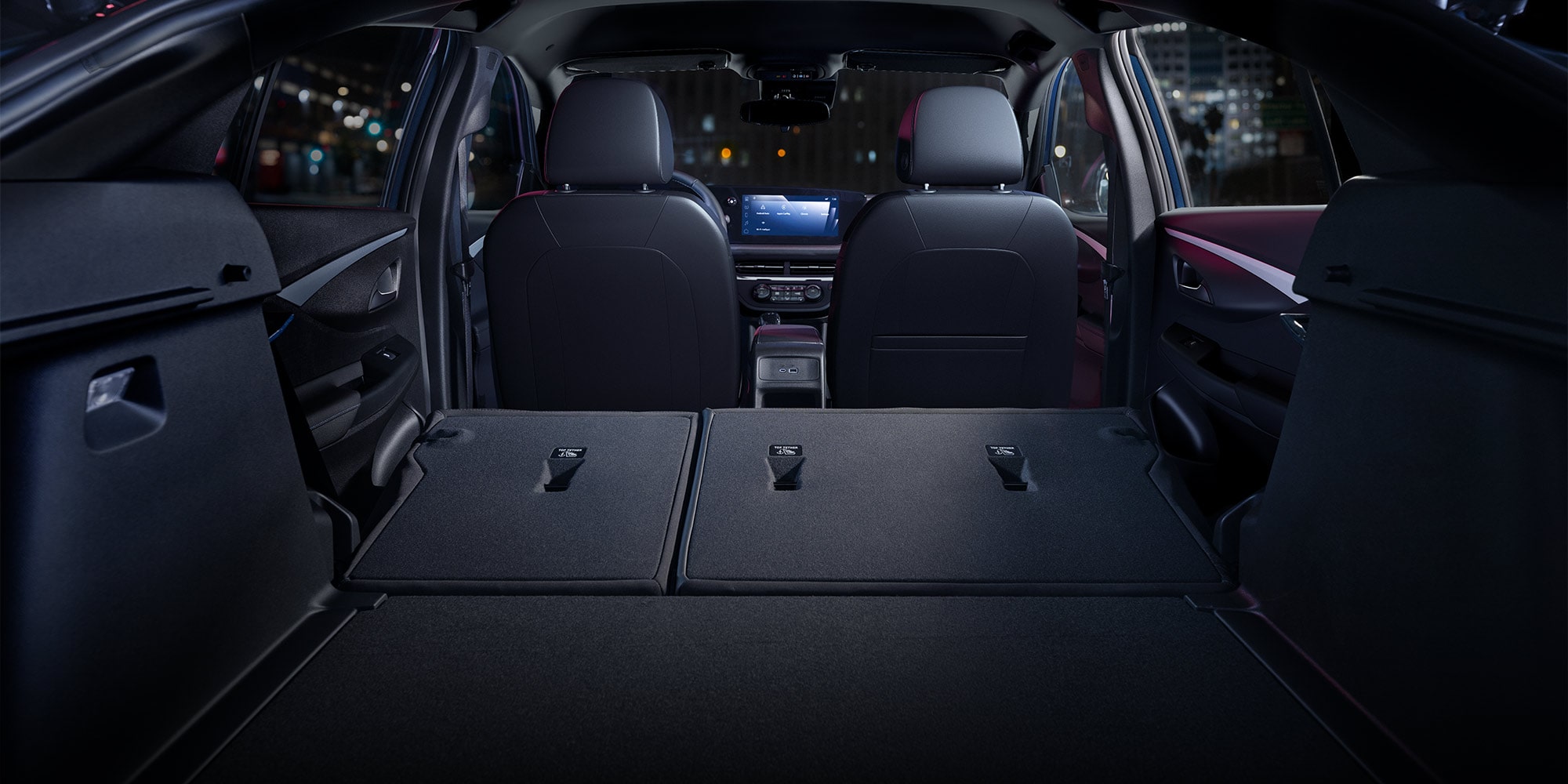 The Rear Interior of a 2026 Buick Envista with Seats Folded Down at Night in a City
