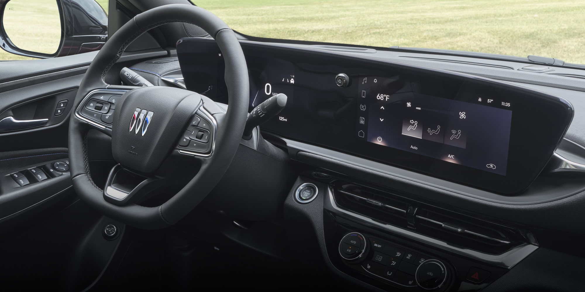 The Interior of a Buick Envista Facing a Grassy Field with a Digital Dashboard and Climate Controls on the Infotainment Screen 
