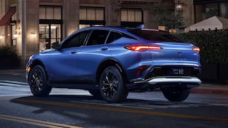 Rear Three-Quarters View of a Buick Envista Compact Crossover Driving Down a City Street at Night