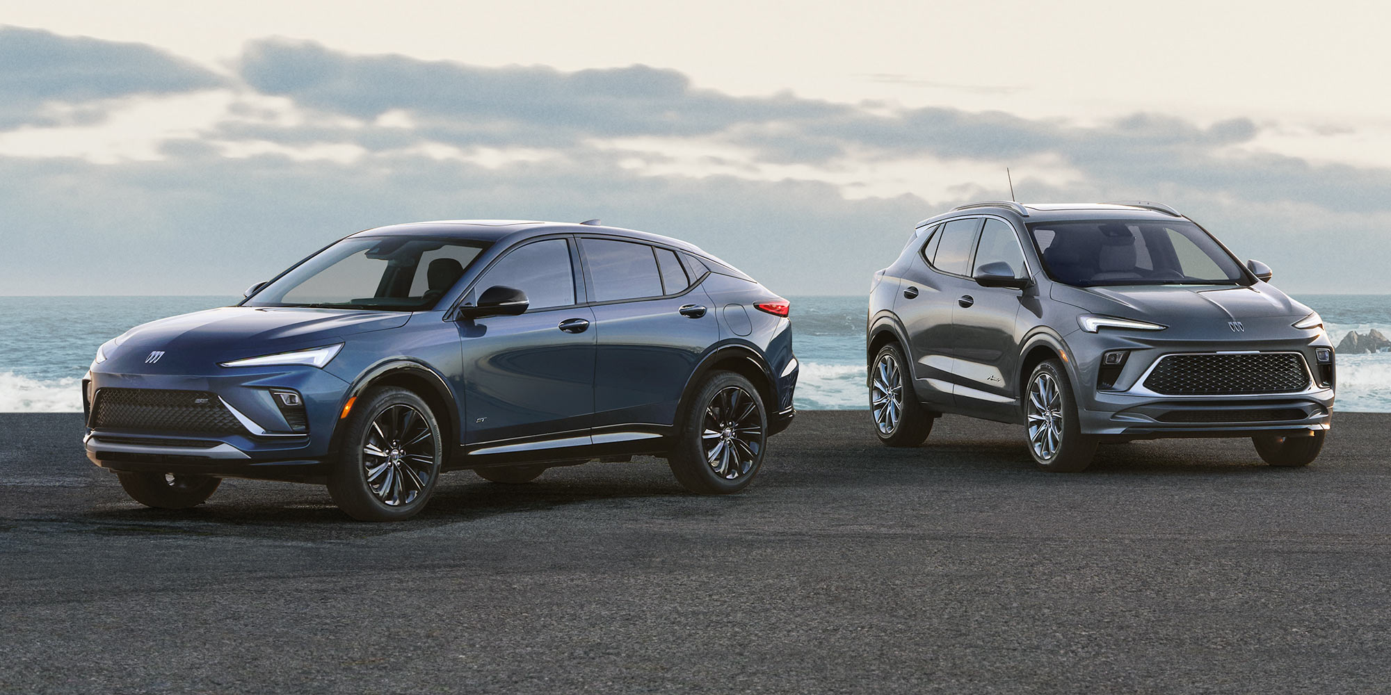 Two Buick Vehicles on an Oceanfront Road Including a Blue Envista and a Gray Encore GX