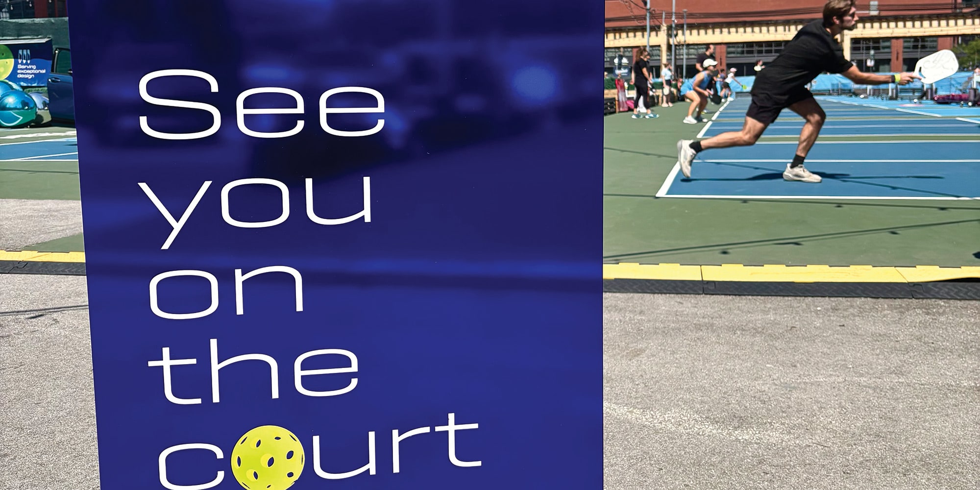 A Blue Sign Displaying See You on the Court with the Buick Logo and a Pickleball Player in the Background