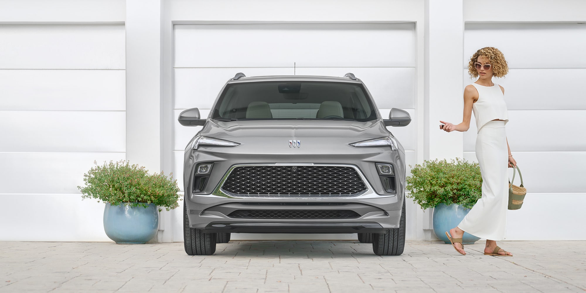 A Woman Walking Away From a 2025 Buick GX Avenir Using Key Remote to Lock Vehicle