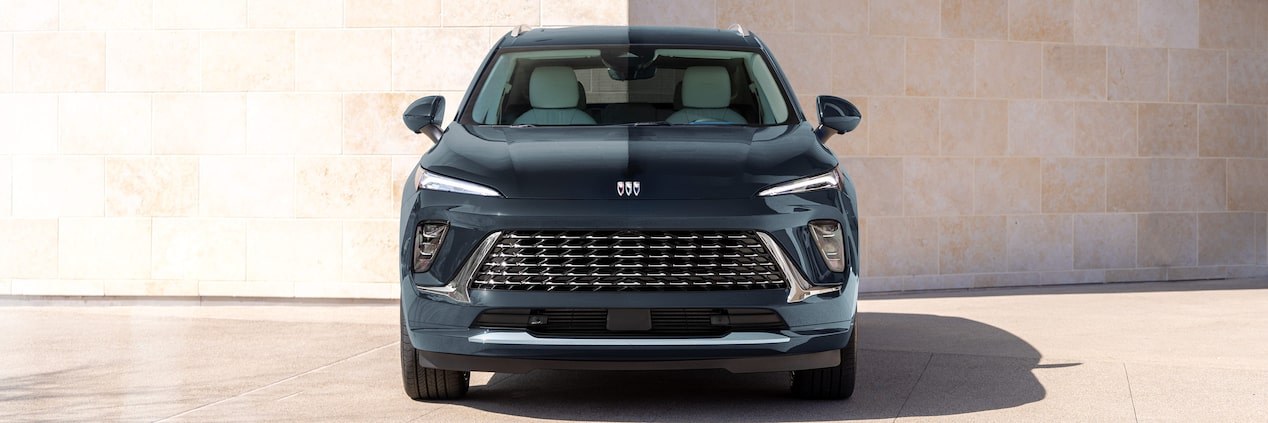 A Front View of a Dark Blue Buick SUV with a Distinctive Grille Parked by a Stone Wall
