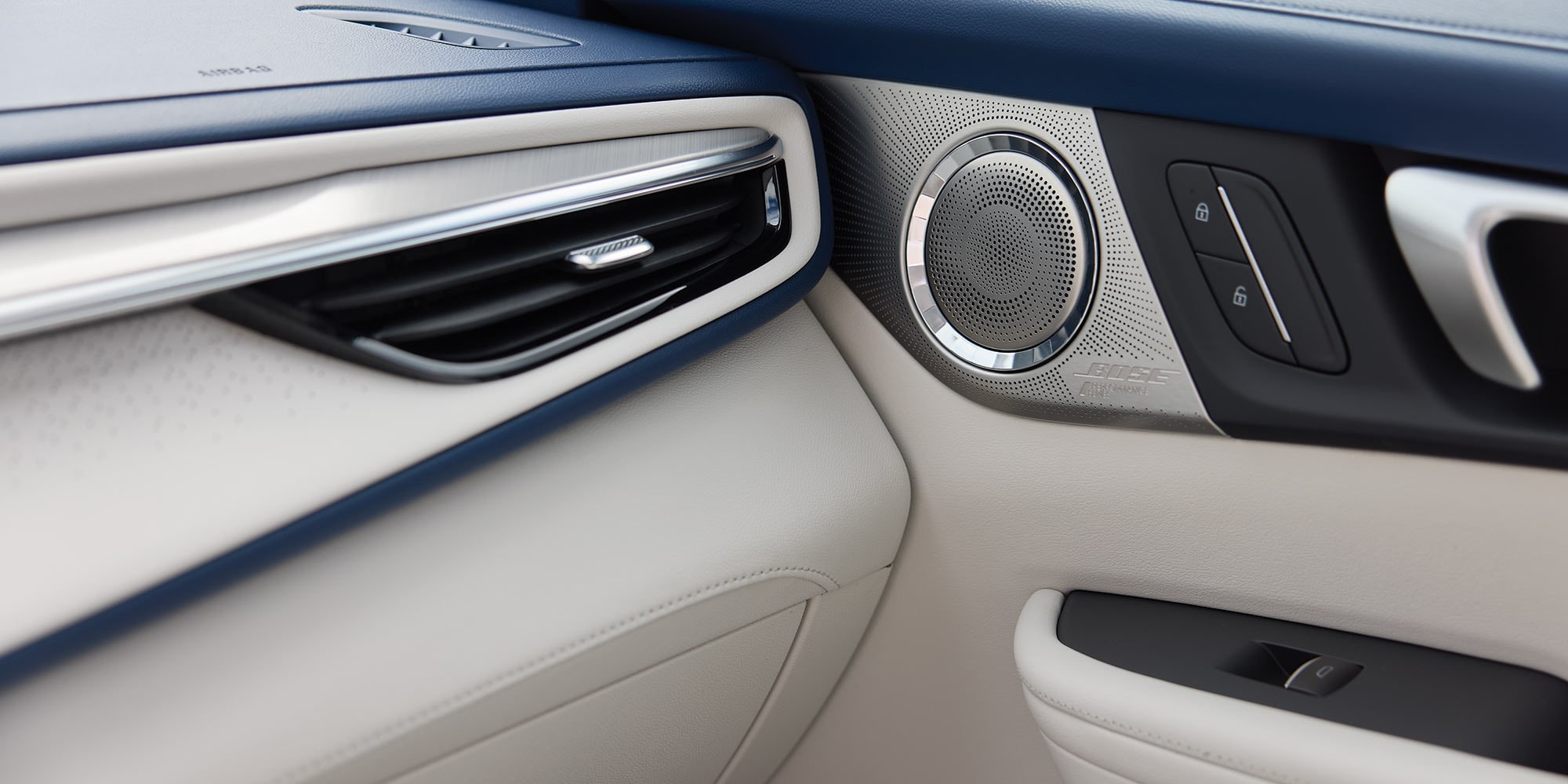 Close-Up of the Luxurious White and Blue Interior of a Buick Vehicle, Featuring a Silver Air Vent and a BOSE Speaker
