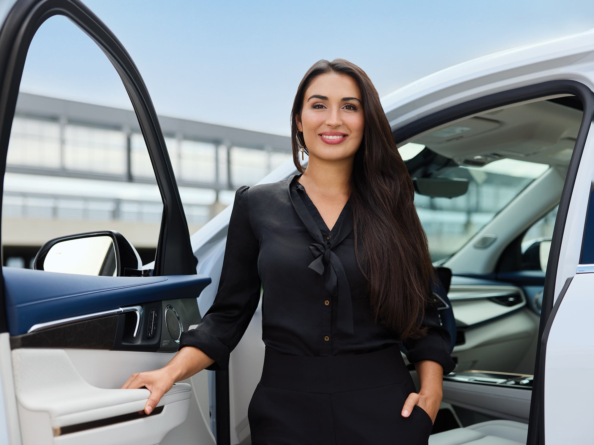 Dalia Elmokadem Stands Smiling by the Open Driver's Side Door of a White Buick Vehicle with Blue and White Interior Accents