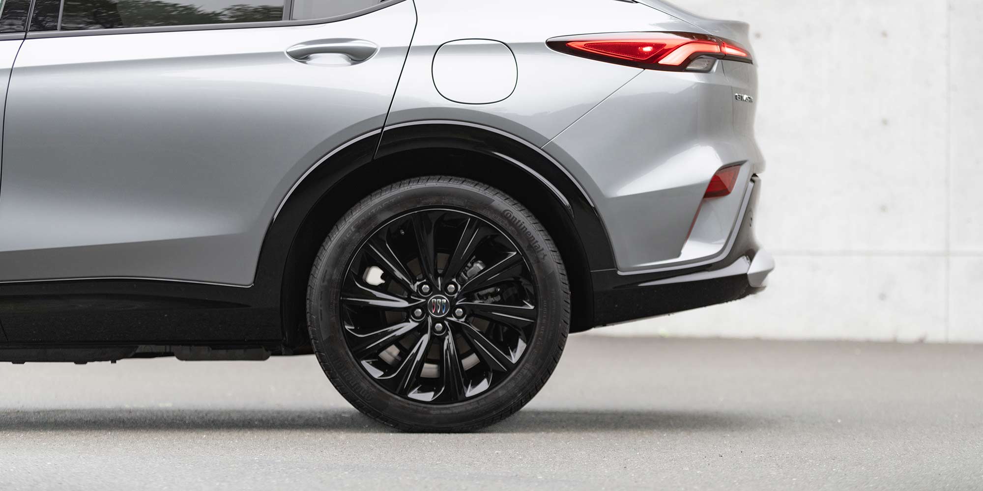 A Close-Up Side View of a Silver Buick SUV's Rear Wheel, Taillight, and Fuel Cap