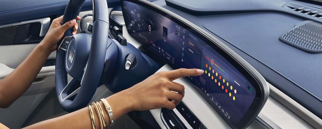 Close-up of a Woman Driving a Buick Enclave While Using the Touchscreen on the Infotainment System