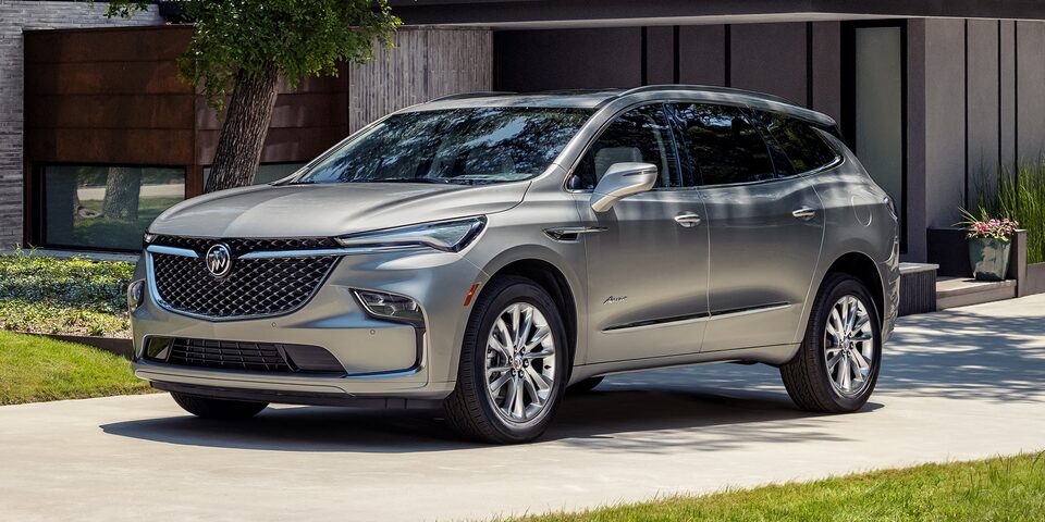 A Couple Enjoys One Another's Company as they Sit In Their Moonstone Metallic Enclave Avenir