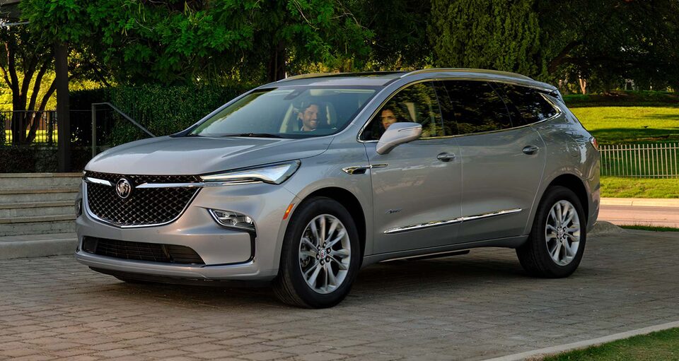 A Couple Enjoys One Another's Company as they Sit In Their Moonstone Metallic Enclave Avenir