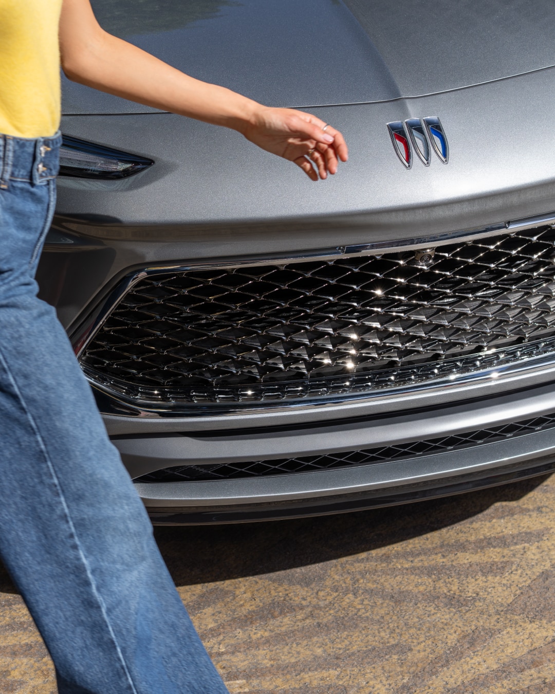 Close-up of a Woman Walking in Front of a Buick Vehicle with a Focus on the Vehicles Grille