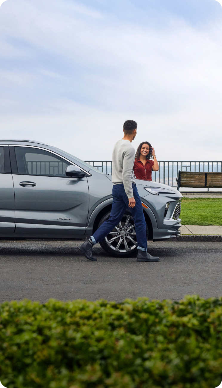 two people walking by a Buick