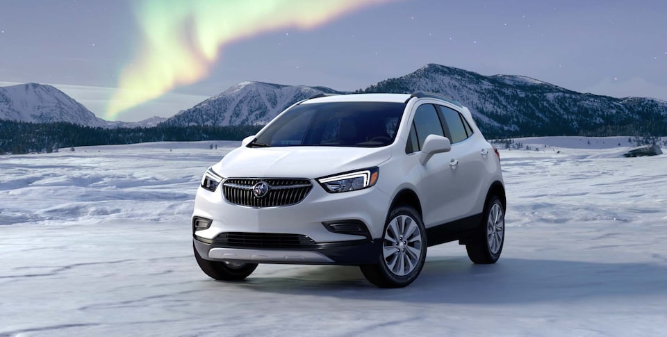 The Buick Encore Parked on a Frozen Lake with a Mountain Backdrop Under the Breathtaking Northern Lights