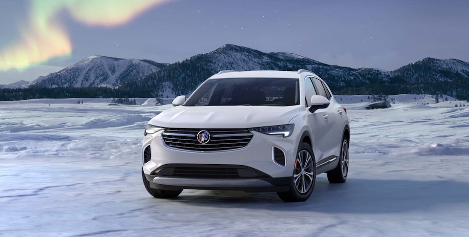 The Summit White Buick Envision Parked on Snow With Mountains In Background