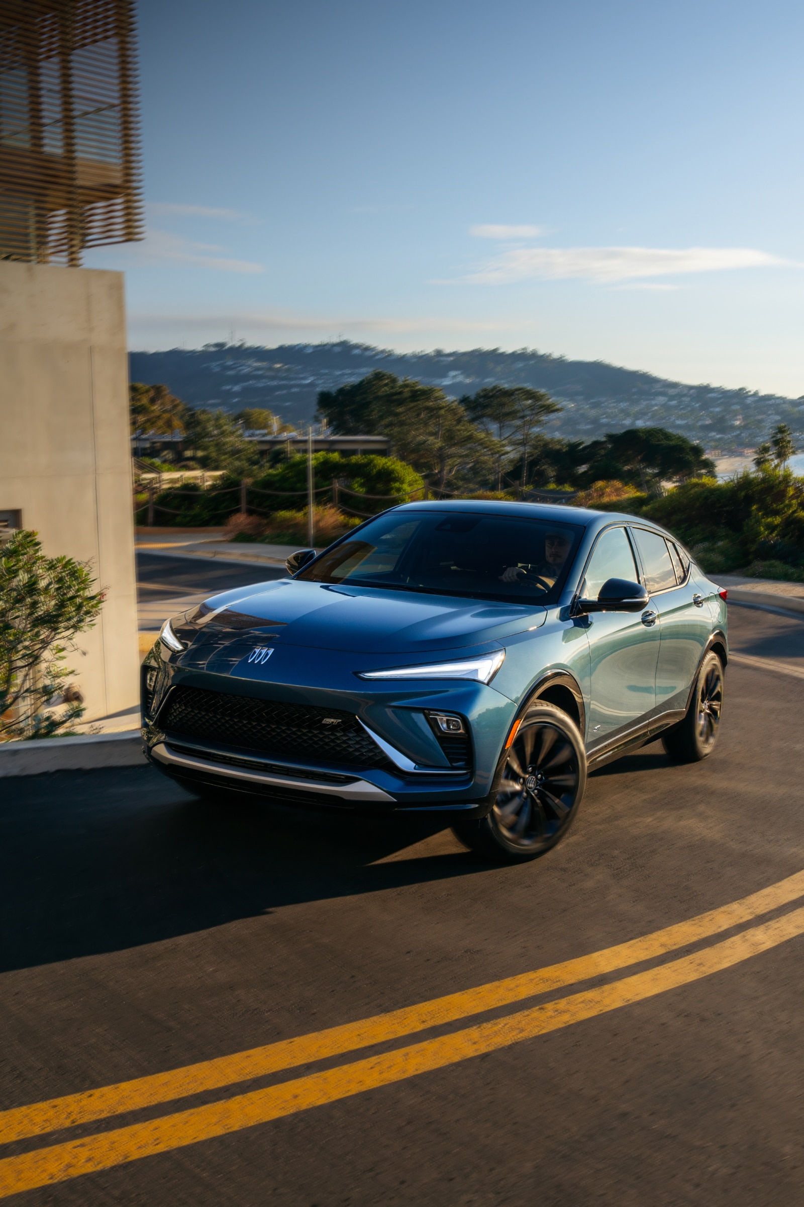 A Blue Buick Envista Crossover SUV Parked On a City Street With Buildings in the Distance