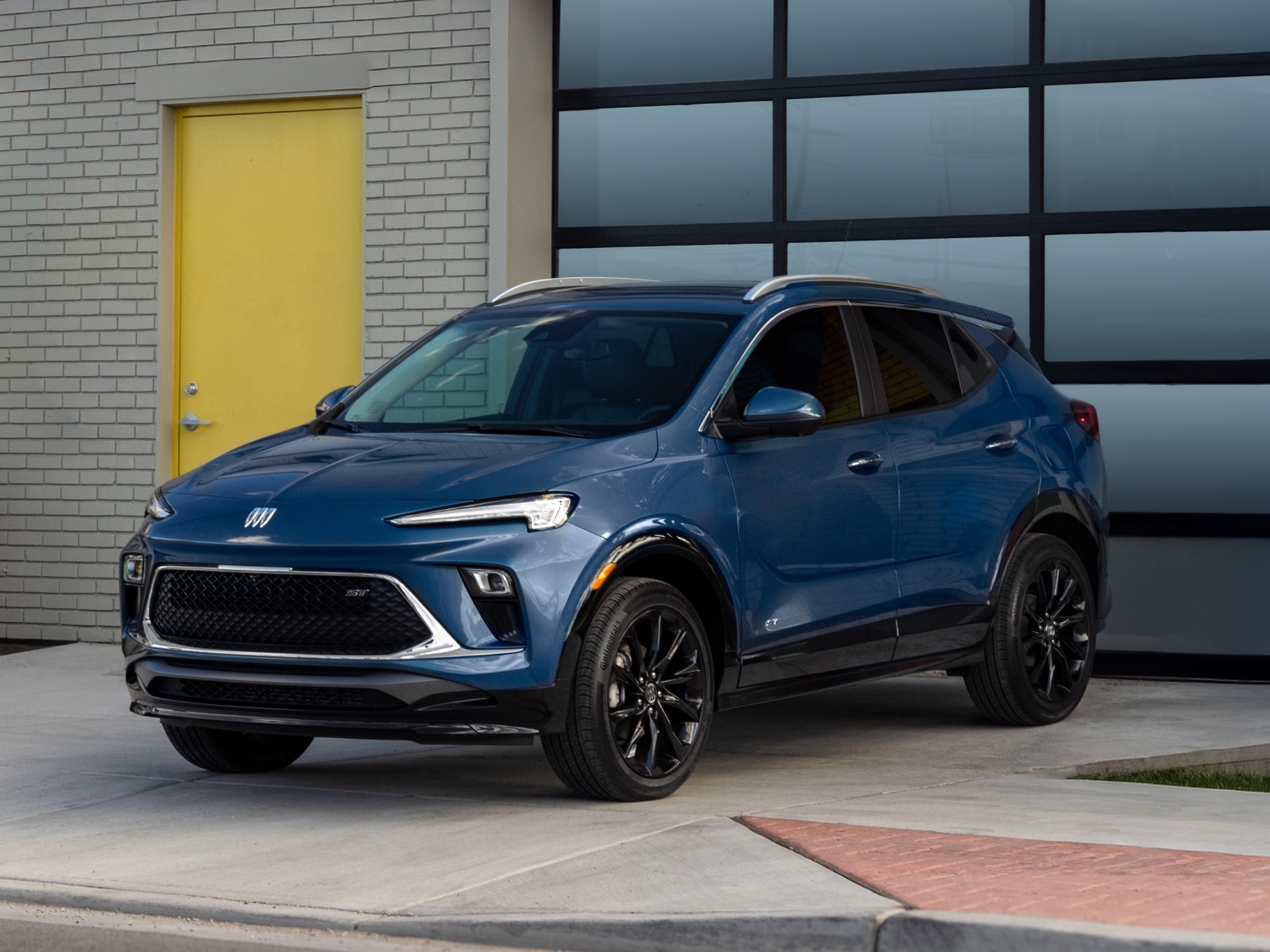 A Blue Buick Encore GX SUV Parked in Front of a Modern Garage Door with a Yellow Accent Door