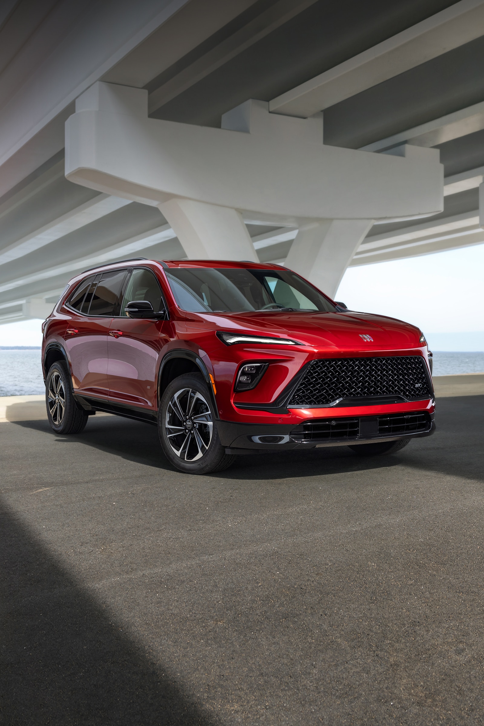 A Red Buick Enclave SUV Parked Under a Concrete Overpass with Water in the Background