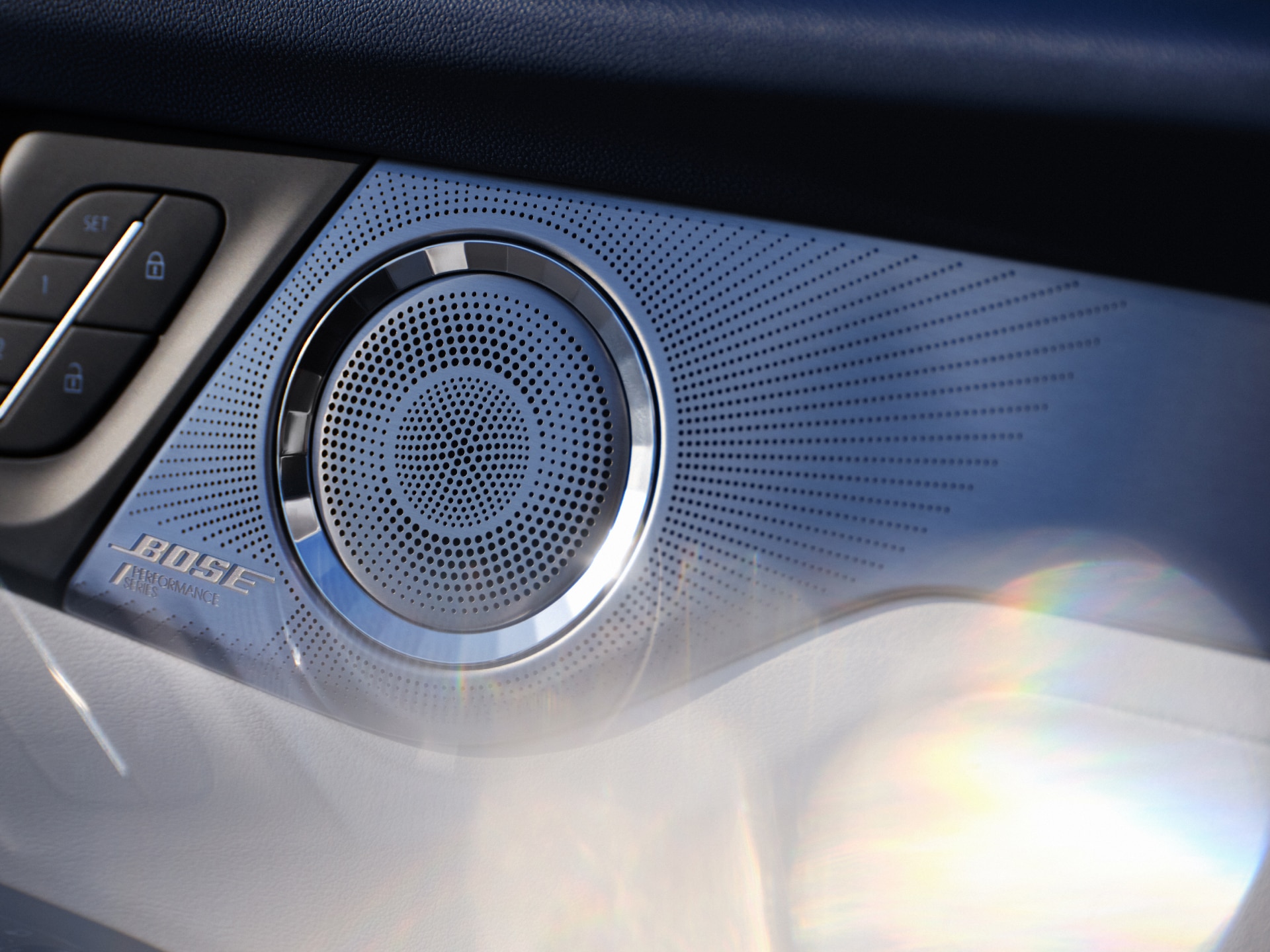 A Close-up of a Car Speaker Grille with a Silver BOSE Logo