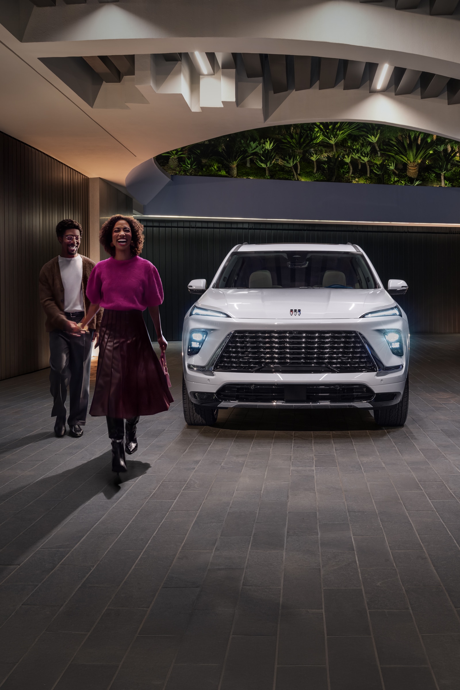 A Couple Holding Hands and Laughing Walking Away From a Buick Enclave SUV Parked Outside
