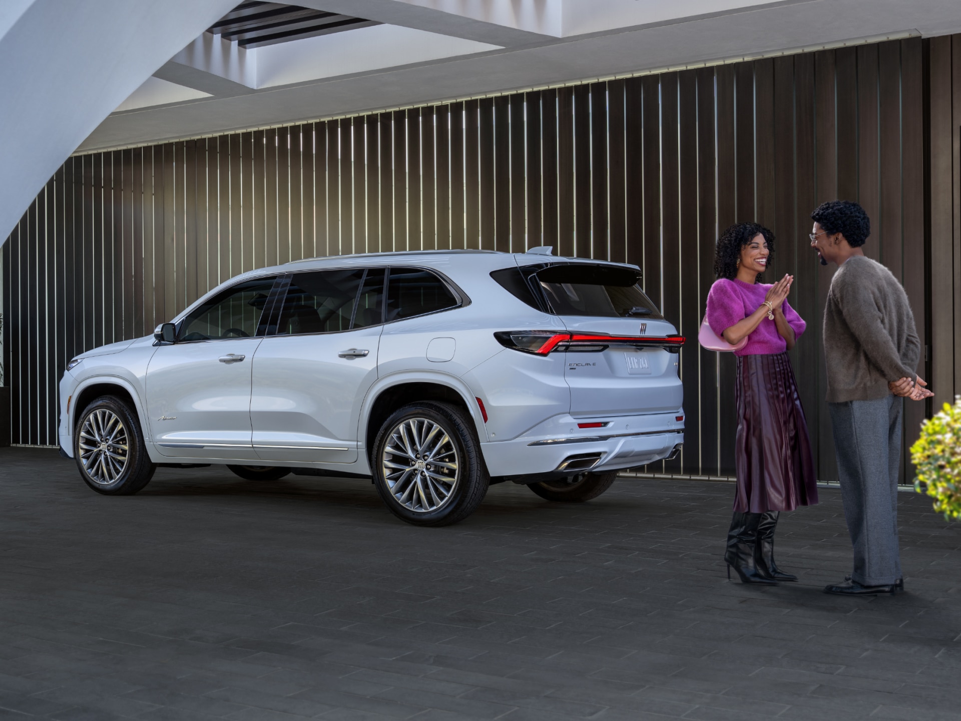 A Man and Woman Smiling by a White Buick Enclave SUV Parked Outside