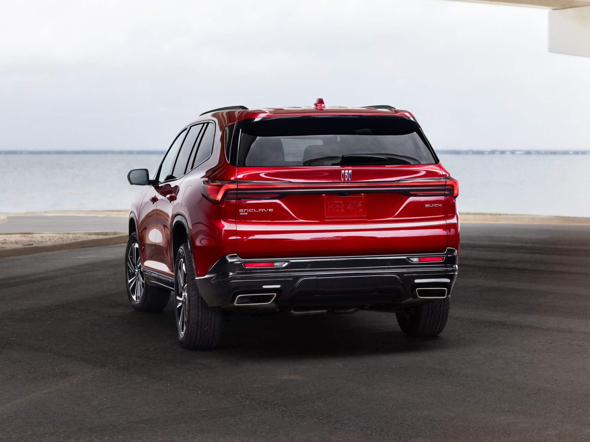 The Rear Angle of a Red Buick Sport Touring SUV Parked Under an Overpass Next to Water