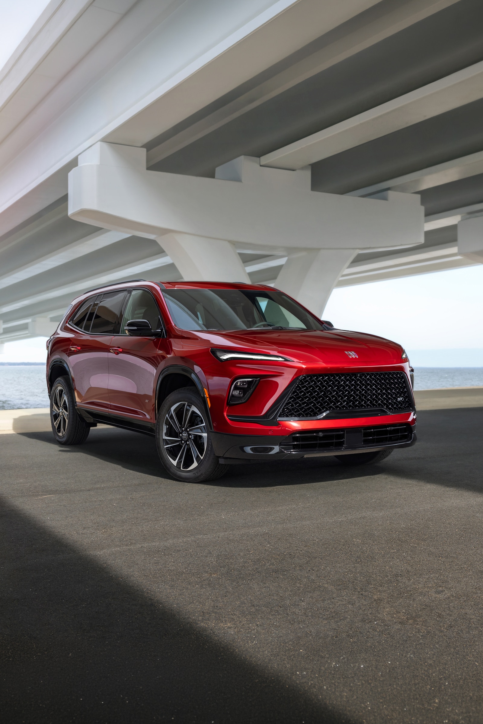 A Red Buick Enclave SUV Parked Under an Overpass Next to the Water
