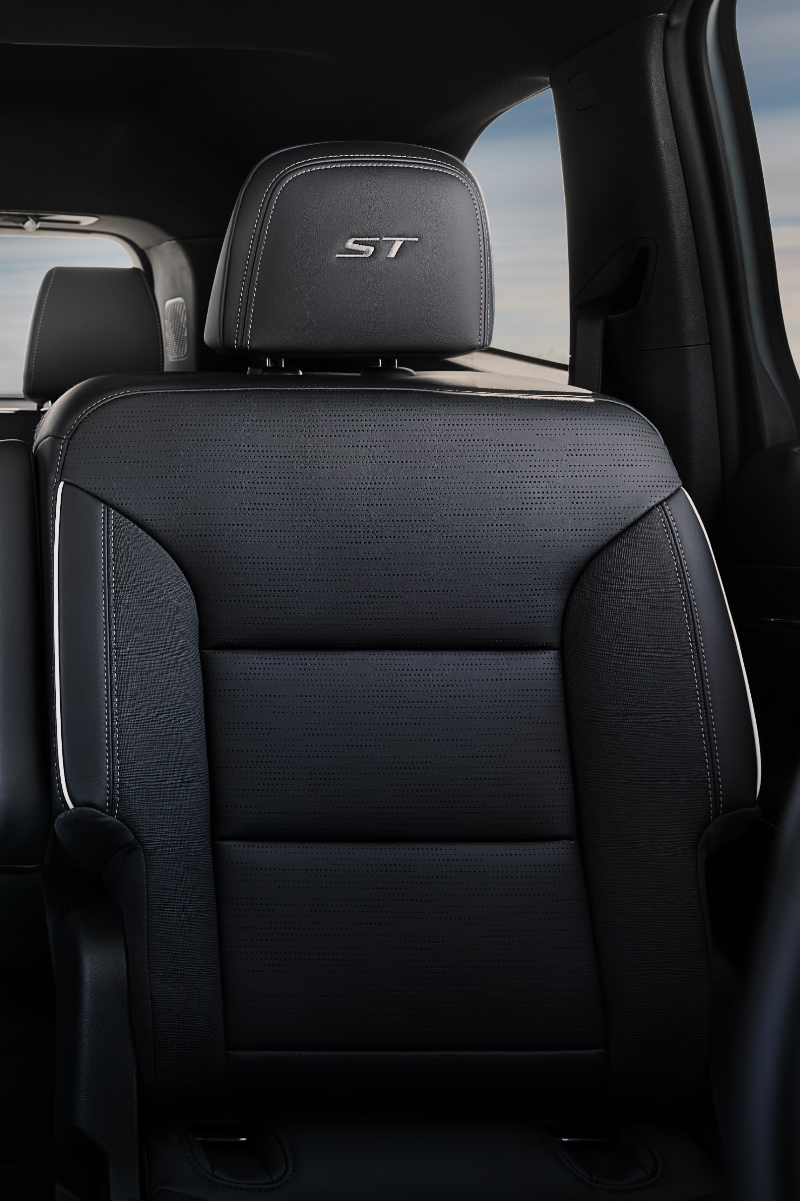 The Interior View of the Rear Passenger Seats of a Buick with Three Rows of Dark Gray Seats