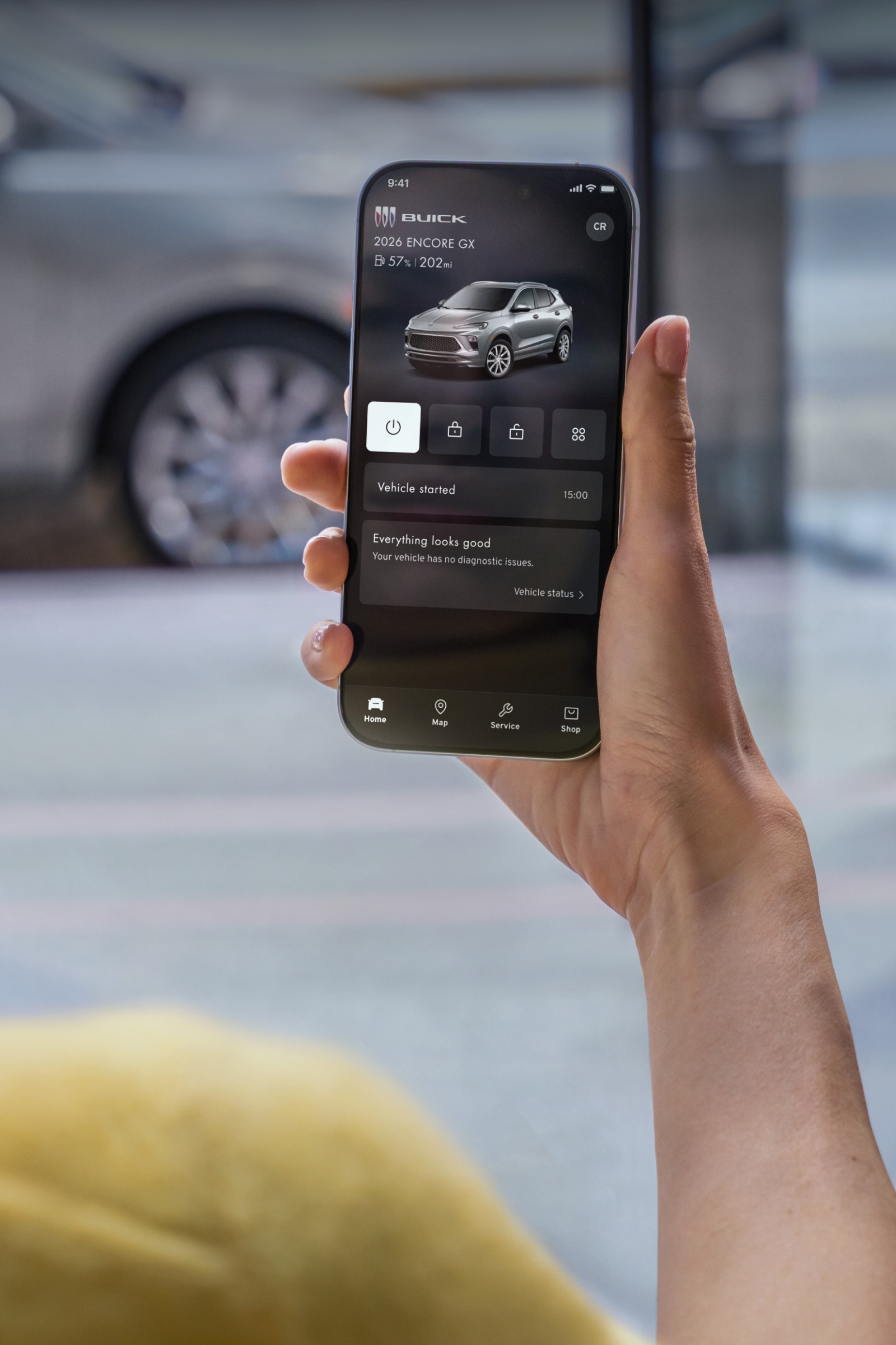 A Woman Holding a Smartphone Displaying the Buick App with Text Comfort and Convenience
